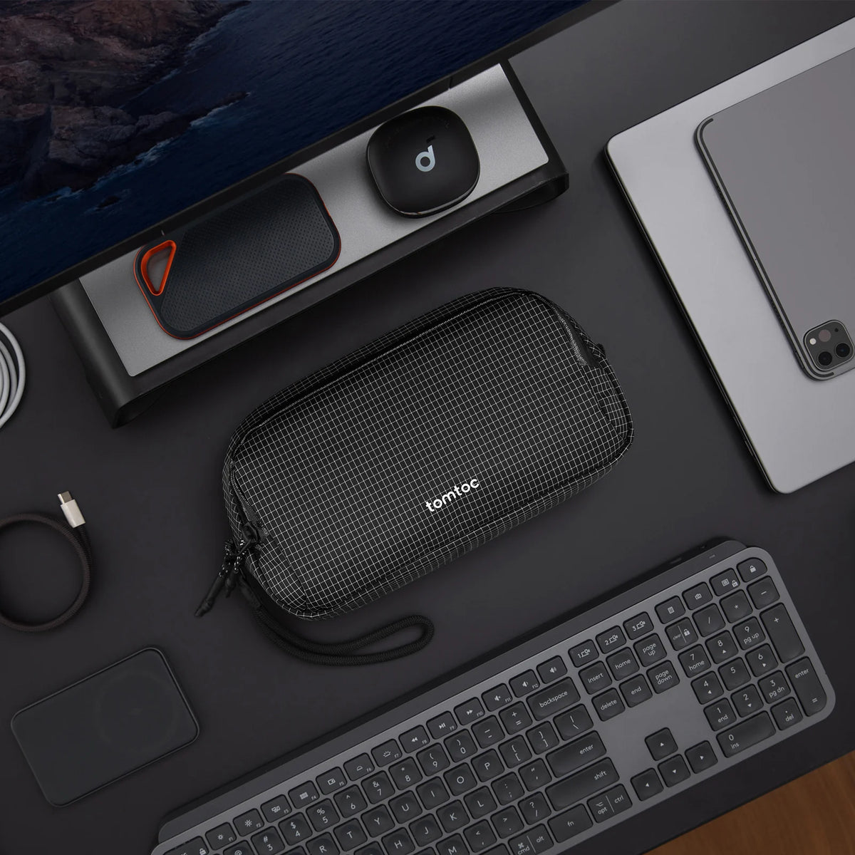 Black T12M1D2 pro organiser pouch with 'tomtoc' branding on a desk with computer equipment.