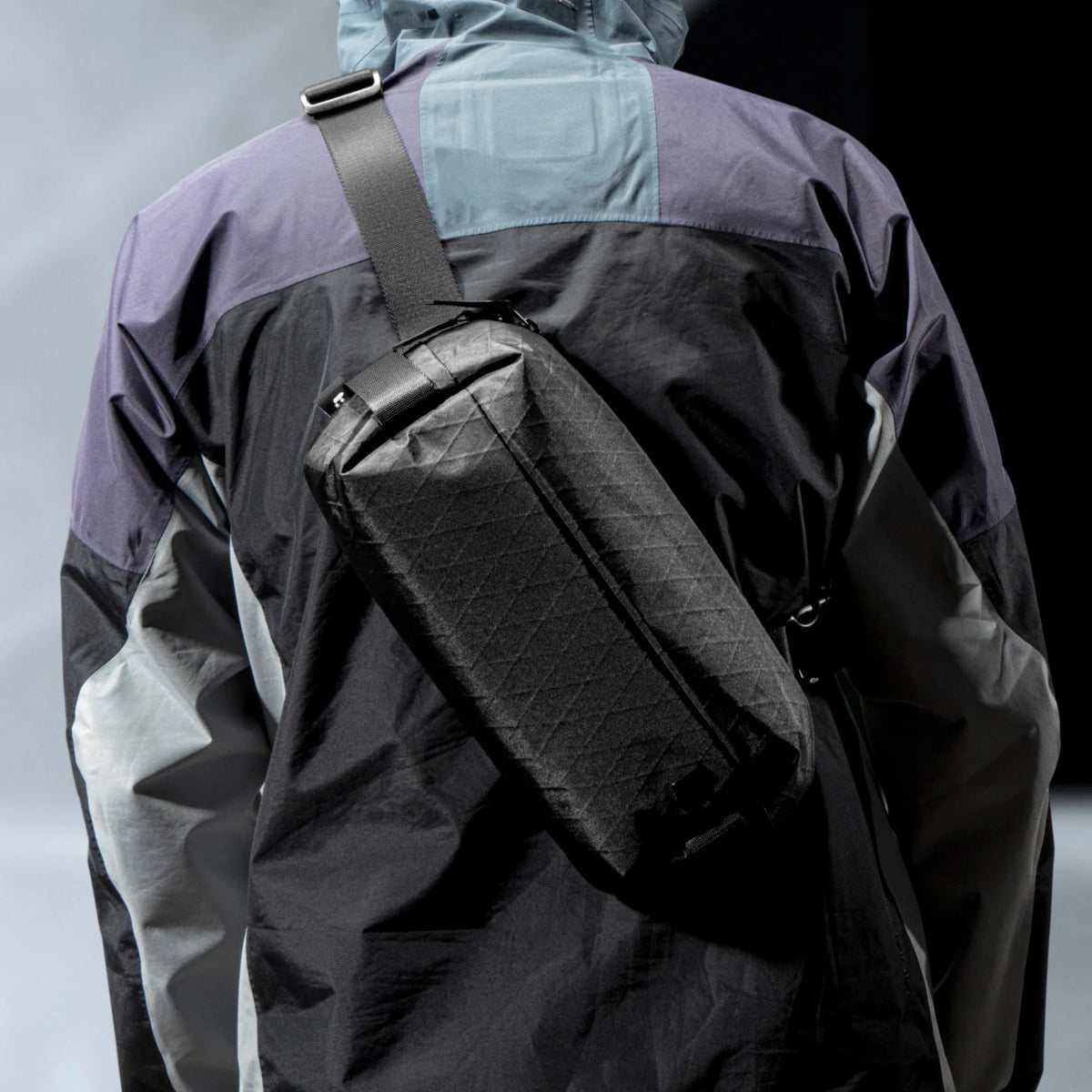 Person wearing a black tomtoc X-Pac Sling Bag Small (3L) T21S1D2 over a gray and purple jacket in outdoor