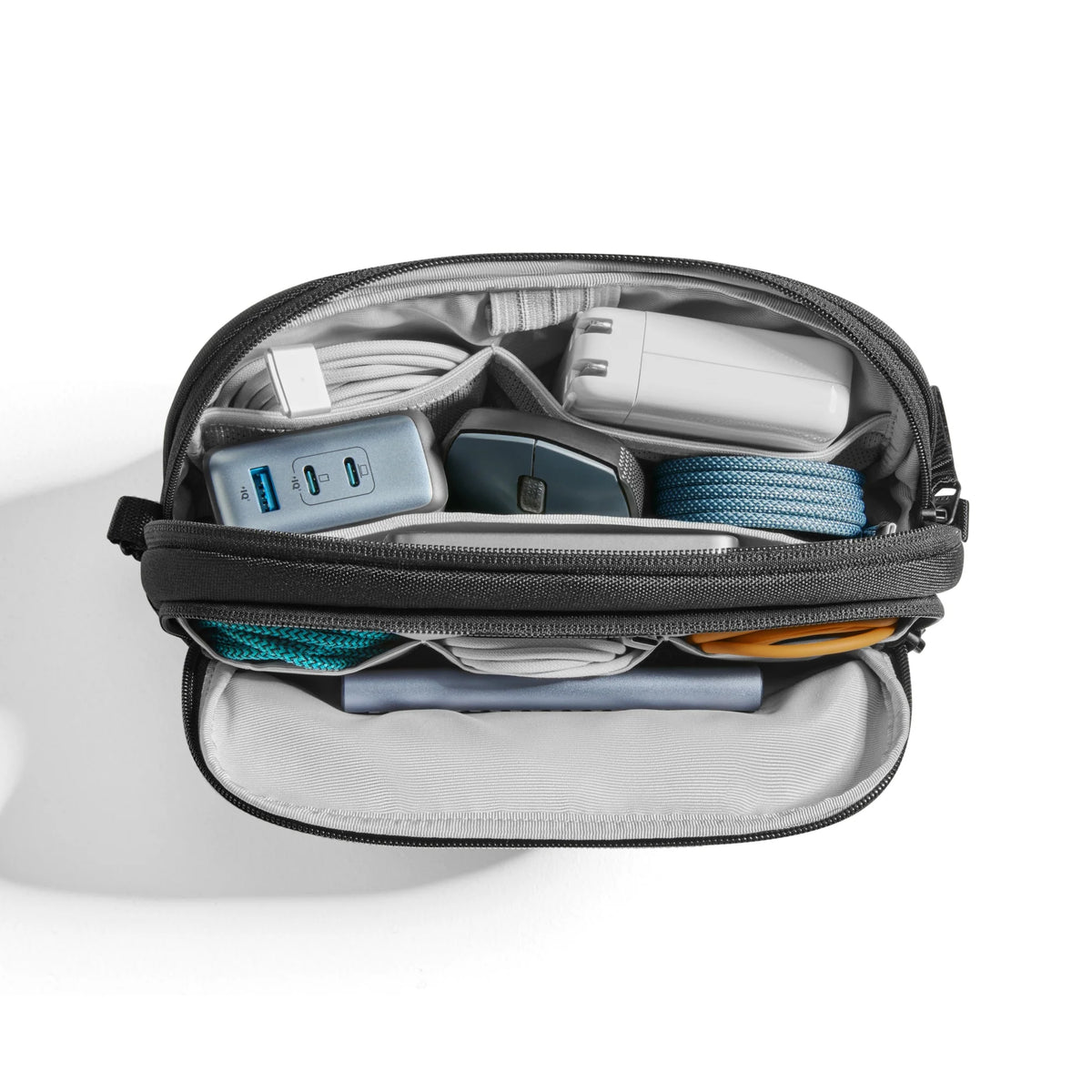 Small black zippered pouch containing electronic accessories on a white background