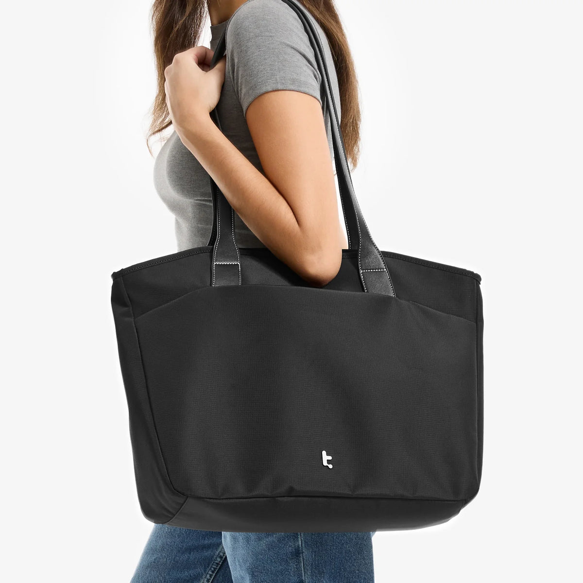 Person holding a tomtoc versatile laptop tote bag large with a visible brand logo on a white background