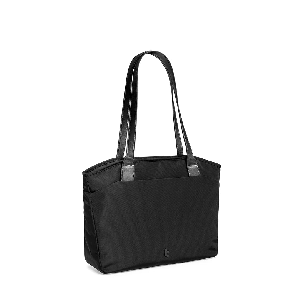 A black tote bag T23S1D1 tomtoc versatile laptop tote bag small with dual shoulder straps and a small tomtoc logo at the bottom center, showing side view against a plain white background