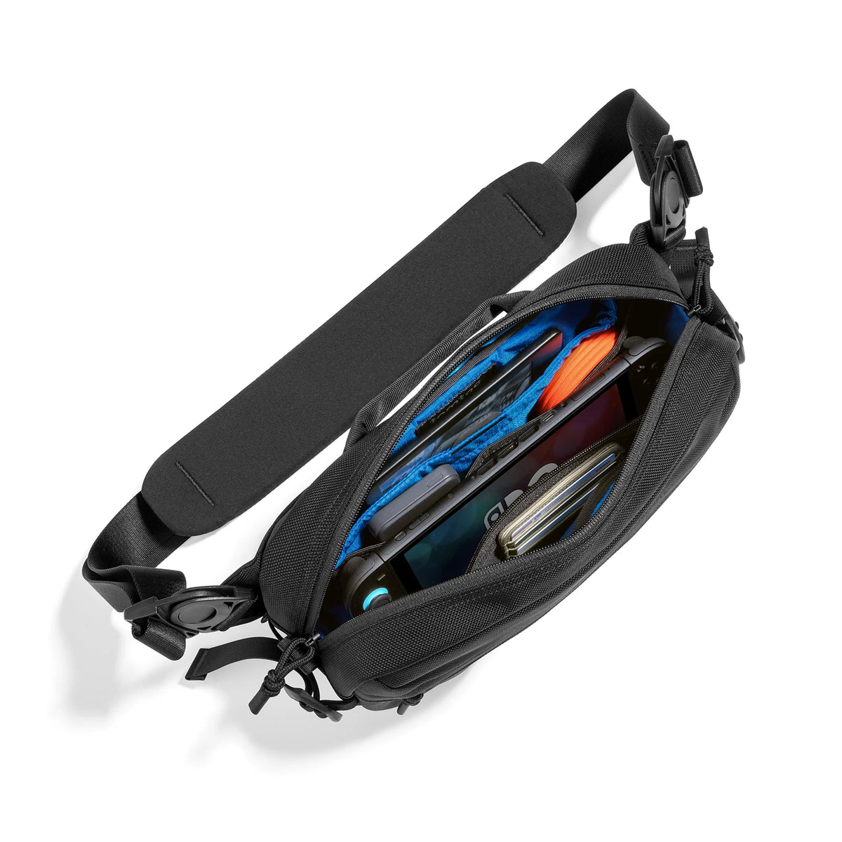 A tomtoc Wander Daily Sling Bag (5.5L) - T26 in black shown open, filled with various items like a blue water bottle, phone, and wallet, on a clean white background.